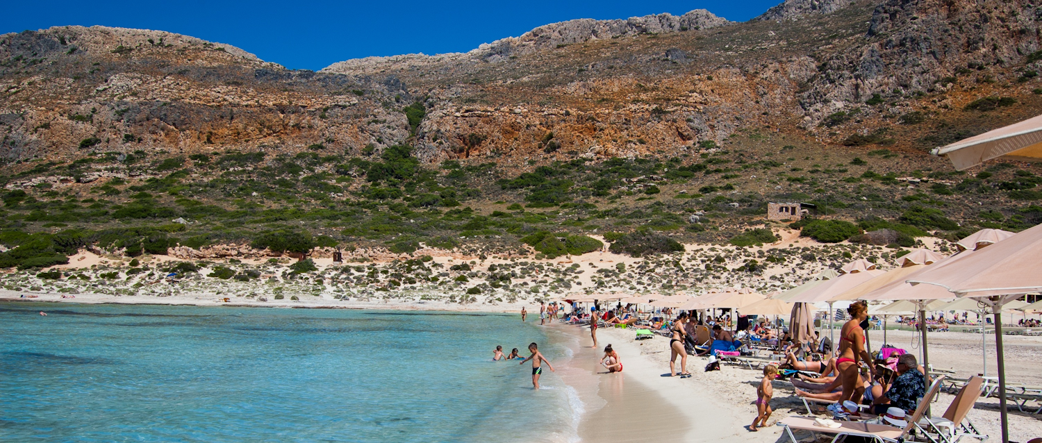 Beach and beachgoers on Crete. Mountains in the background